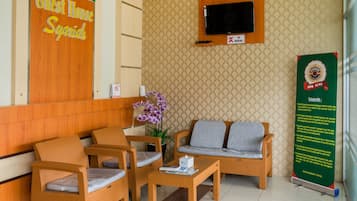 A reception area with wicker furniture, a television, and a signboard.