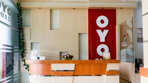A reception desk with a wooden design and a red accent wall. - OYO 2199 Mandiri Guest House (Banuhampu)