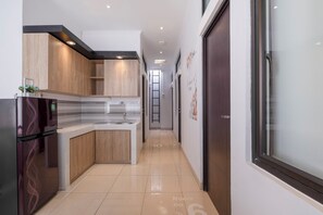 Uma cozinha moderna com armários de madeira, uma geladeira de aço inoxidável e um revestimento de azulejos.