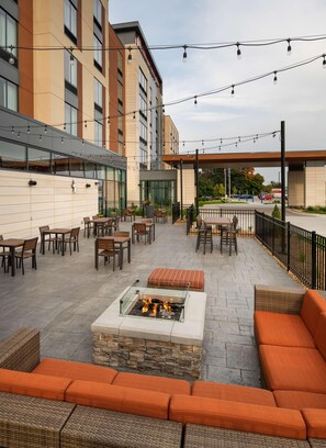 An outdoor patio area with seating, a fire feature, and string lights. - Hilton Garden Inn Milwaukee Brookfield Conference (Milwaukee)