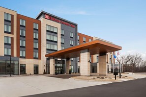 A modern hotel with a prominent entrance, a covered waiting area, and an American flag.