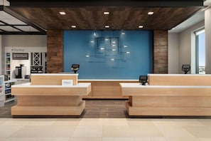 Un mostrador de recepción de hotel con pared azul, zona de recepción de madera y una lámpara moderna.