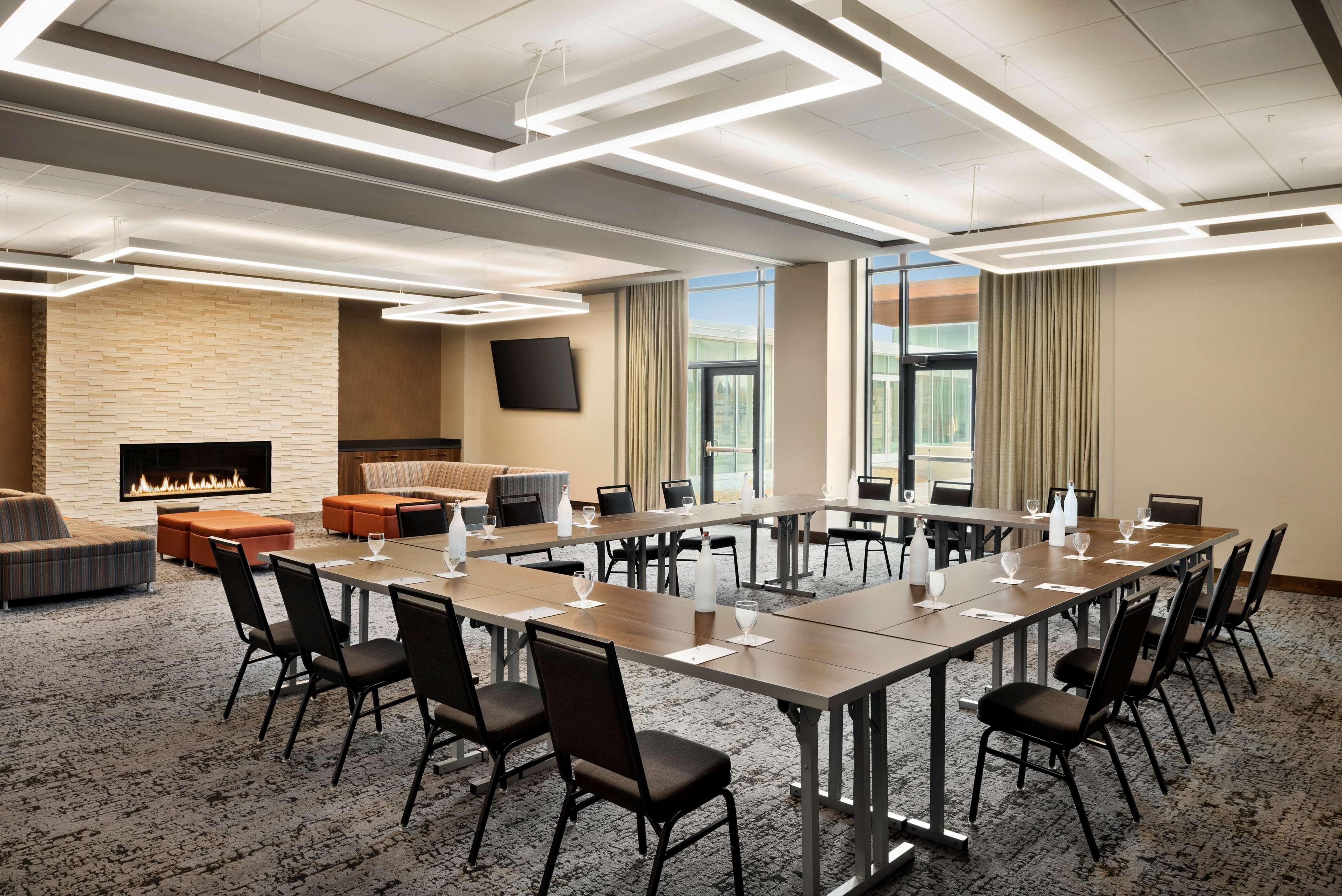 A conference room with a long table, chairs, a fireplace, and a TV on the wall.