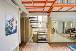 A staircase leading to a balcony, a dining area with a table and chairs, and a painting on the wall. - OYO 3300 Nadjara Residence (Jakarta)