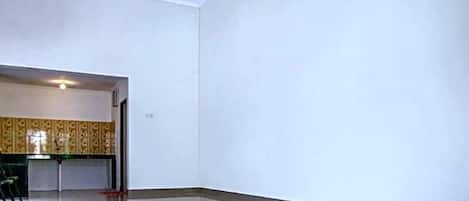 A spacious room with a large window, a flat floor, and a door leading to another area.