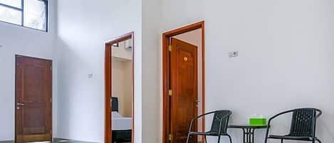 A hallway with two wooden doors, a small table with chairs, and a window providing natural light.
