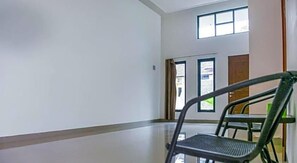 A hallway with a chair, a door, and windows. - OYO 3438 Pasir Padi Inn Syariah (Pangkalpinang)