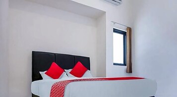 Una habitación de hotel con una cama, un ventanal y aire acondicionado instalado en la pared.