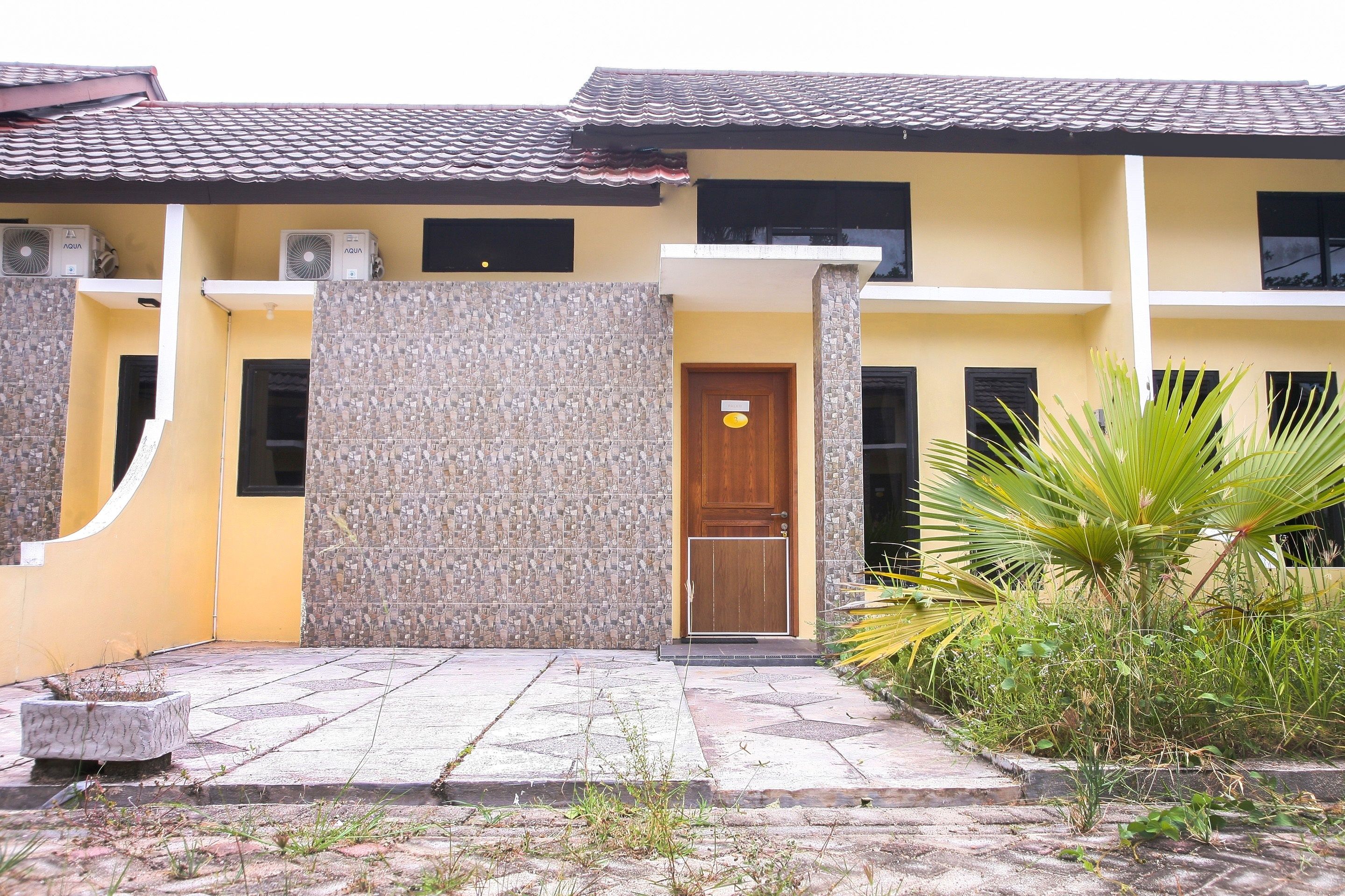 A two-story building with a tiled roof, a wooden door, and air conditioning units on the upper floor.