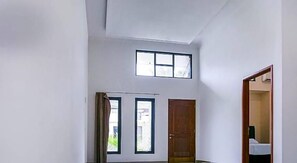 A room with a high ceiling, a wooden door, and two windows. - OYO 3438 Pasir Padi Inn Syariah (Pangkalpinang)