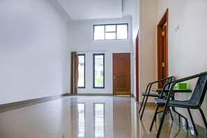A hallway with a polished floor, two doors, and a bench.