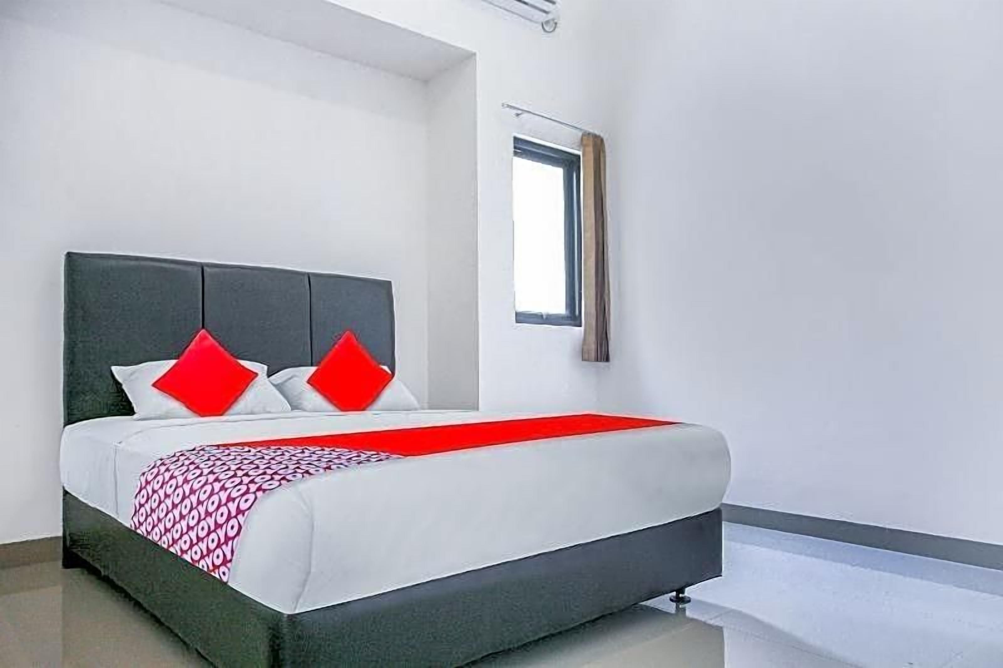 A modern bedroom with a bed, pillows, and a window.