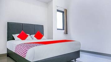A modern bedroom with a bed, pillows, and a window.