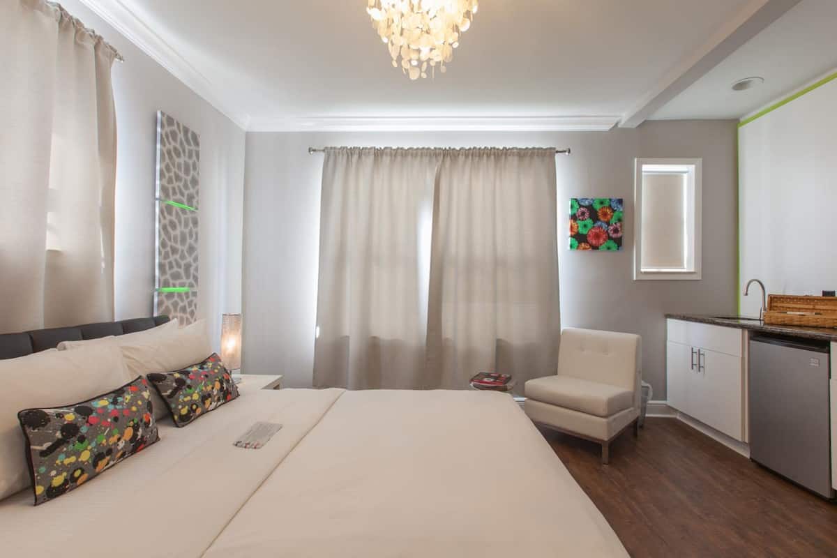 Quarto de hotel com cama, cadeira, escrivaninha e espelho.