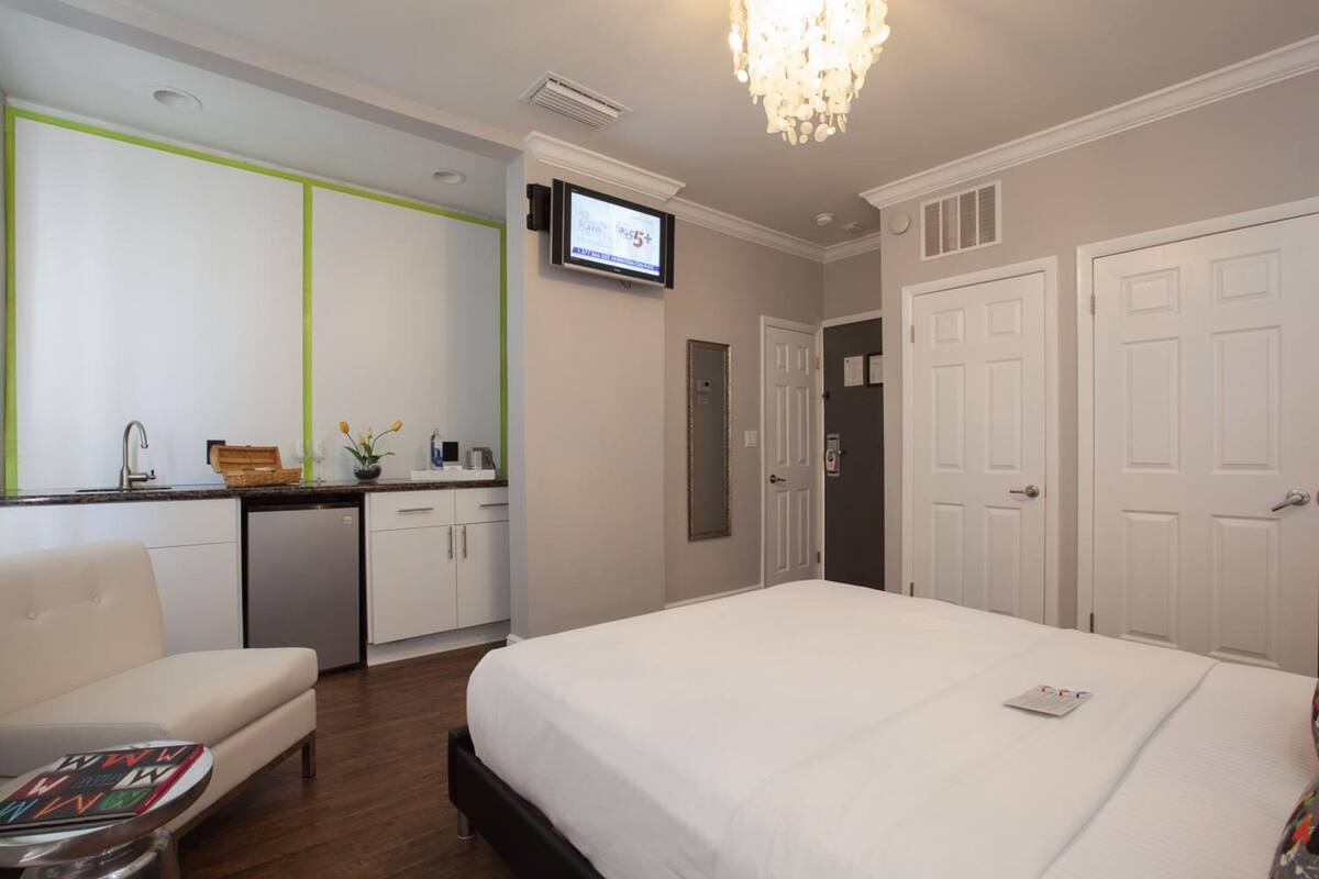 A hotel room with a bed, a desk, a chair, a TV, and a wardrobe.