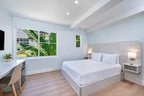 Une chambre moderne avec un grand lit, un bureau et une fenêtre donnant sur un paysage verdoyant.