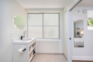 Une salle de bain moderne avec une grande fenêtre, un lavabo et un miroir.