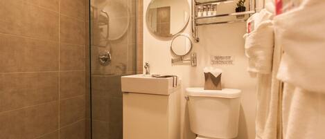 A bathroom with a glass-enclosed shower, a toilet, a sink, and a towel rack.