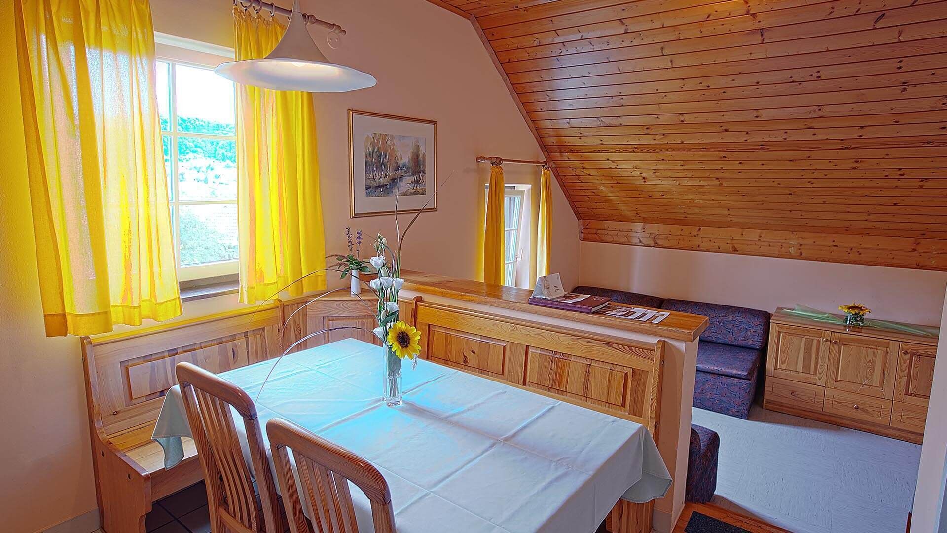 Una habitación acogedora con una mesa de comedor, sillas, un banco y techo de madera.