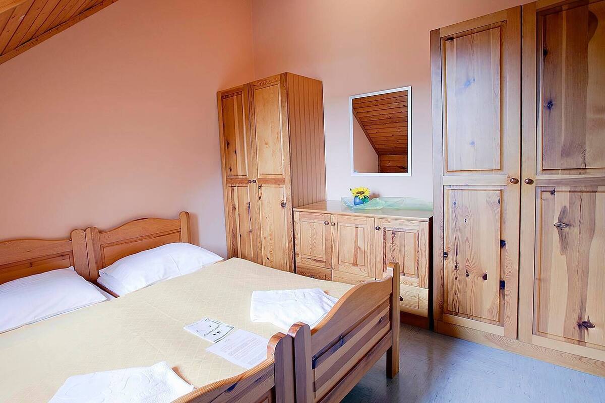 Ein Schlafzimmer mit einem hölzernen Bett, einer Holzkommode und einem Spiegel an der Wand.