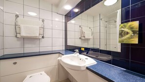 Um banheiro com azulejos brancos, bancada azul, pia branca e um espelho.