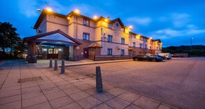 A multi-story hotel with a covered entrance, parking area, and a row of parked cars. - The Magnum Hotel Sunderland Sure Collection By Bw (Sunderland)