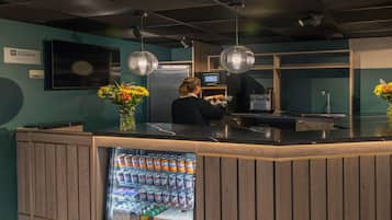 A reception area with a counter, a refrigerator stocked with beverages, and a TV screen.