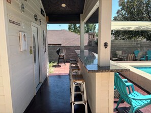 An outdoor patio area with a pool, bar stools, and outdoor seating.