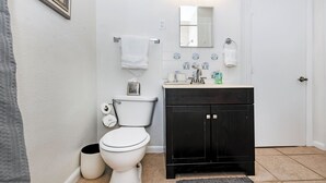 Un bagno con un water bianco, un armadietto nero e uno schienale piastrellato.