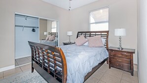 Una camera da letto con un letto, un armadio, un comodino, una lampada e una ventola a soffitto.