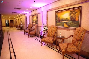 A hotel lobby with patterned chairs, a reception desk, and a large landscape painting on the wall. - Royal Sea View (Alexandria)