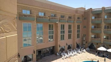 Un hotel a più piani con balconi, sedute all'aperto e una piscina.