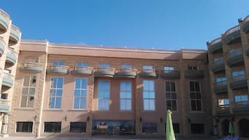 Un edificio a più piani con piscina, balconi e sedie a sdraio.