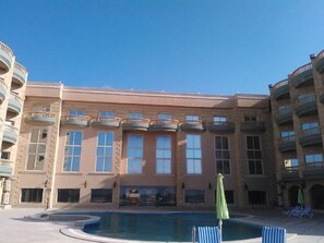 Un edificio a più piani con piscina, balconi e sedie a sdraio.