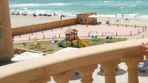 A beach view with a playground, a pool, and a building in the background. - Royal Sea View (Alexandria)
