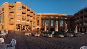 A hotel with a curved facade, multiple balconies, outdoor seating, and a swimming pool. - Royal Sea View (Alexandria)