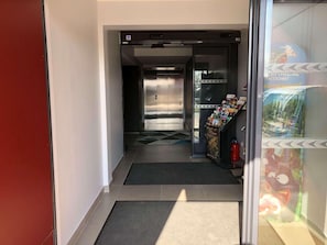 A hotel entrance with a reception desk, a glass door, and a poster advertising a ride. - Akena City Paris Nord Saint Witz (Saint-Witz)