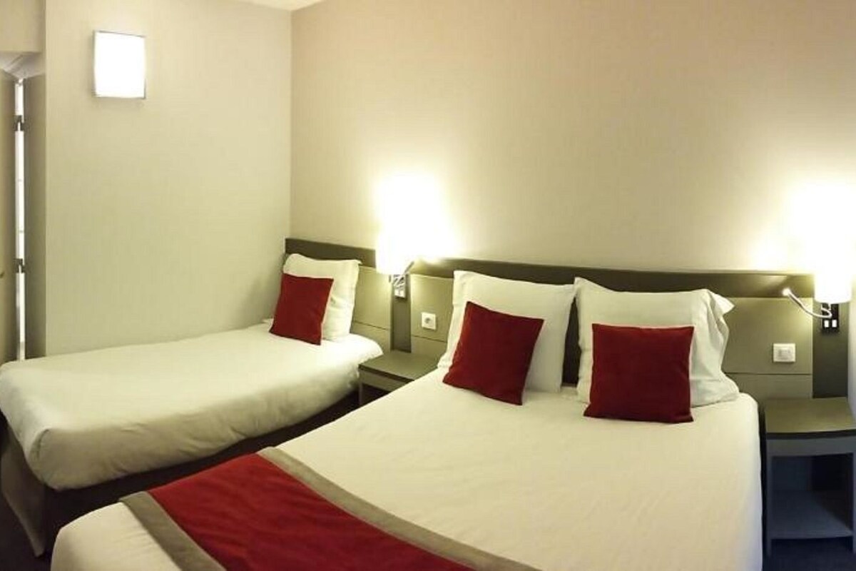 Une chambre d’hôtel avec deux lits, une table de chevet, une lampe et une porte.