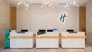 A reception desk area with three counters, a large wall-mounted sign, and a chandelier. - Holiday Inn Xian High Tech Zone (Xi'an)