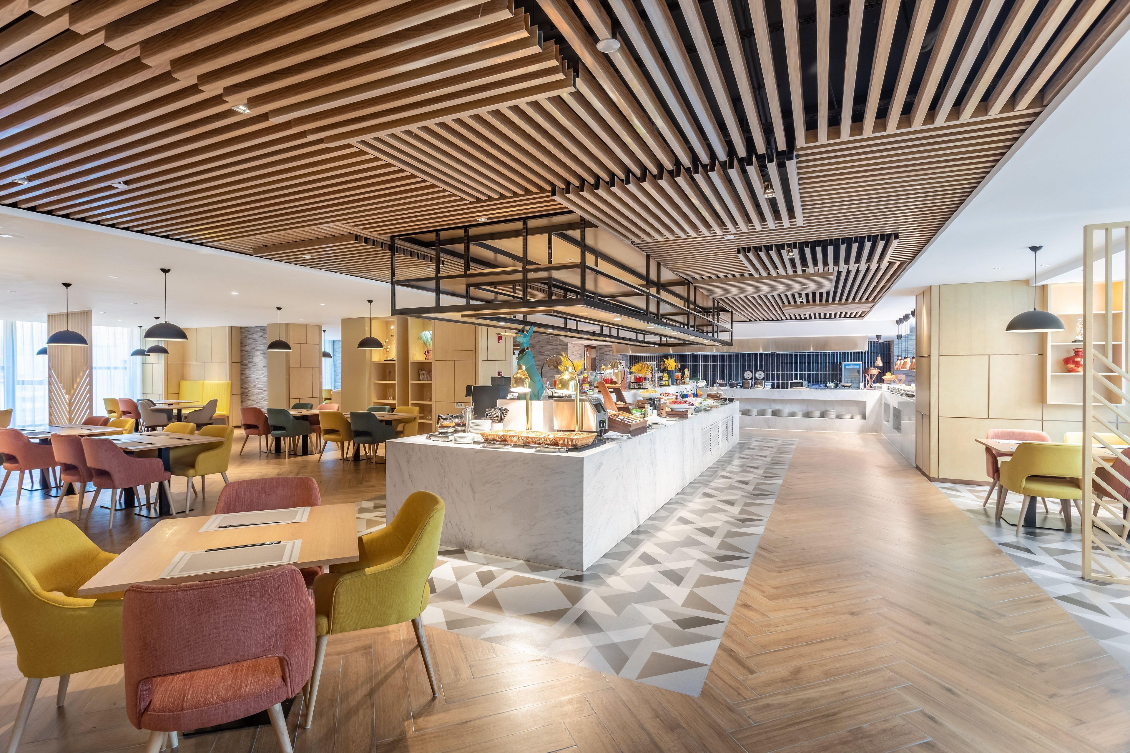 A modern interior with a central island, wooden ceiling, and a geometric patterned floor.