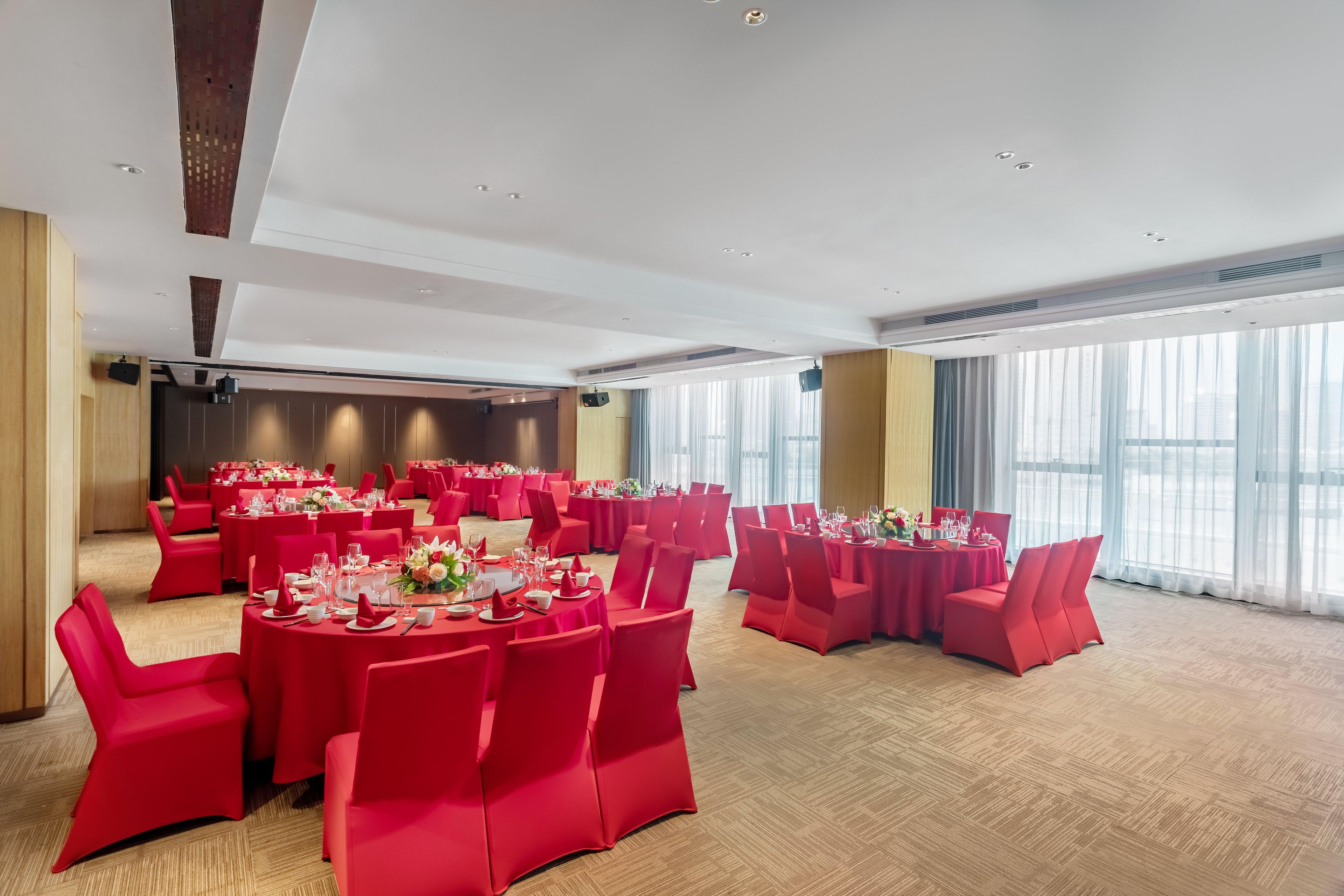A conference room with round tables, red chairs, and large windows.