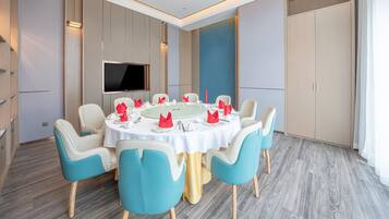 A conference room with a round table, chairs, a flat-screen TV, and a large cabinet.