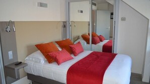 A modern hotel room with a bed, a nightstand, a mirror, and a sliding door. - Hôtel du Parc, Rte Le Rouget de Lisle (Lons-le-Saunier)