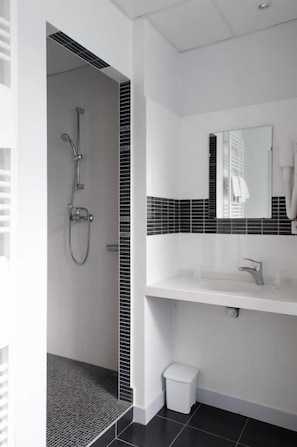 Un baño moderno con ducha, lavamanos e inodoro.