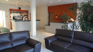 A lobby with two dark brown leather sofas, a reception desk, and a plant. - Hôtel du Parc, Rte Le Rouget de Lisle (Lons-le-Saunier)
