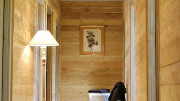 Un couloir en bois avec un banc, un tableau encadré au mur et un lampadaire.