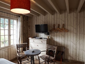 A room with a television, a round table, and two chairs. - Hôtel Le Grand Cerf (Lyons-la-Foret)