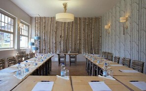 Een congreszaal met lange tafels, stoelen en een kroonluchter.