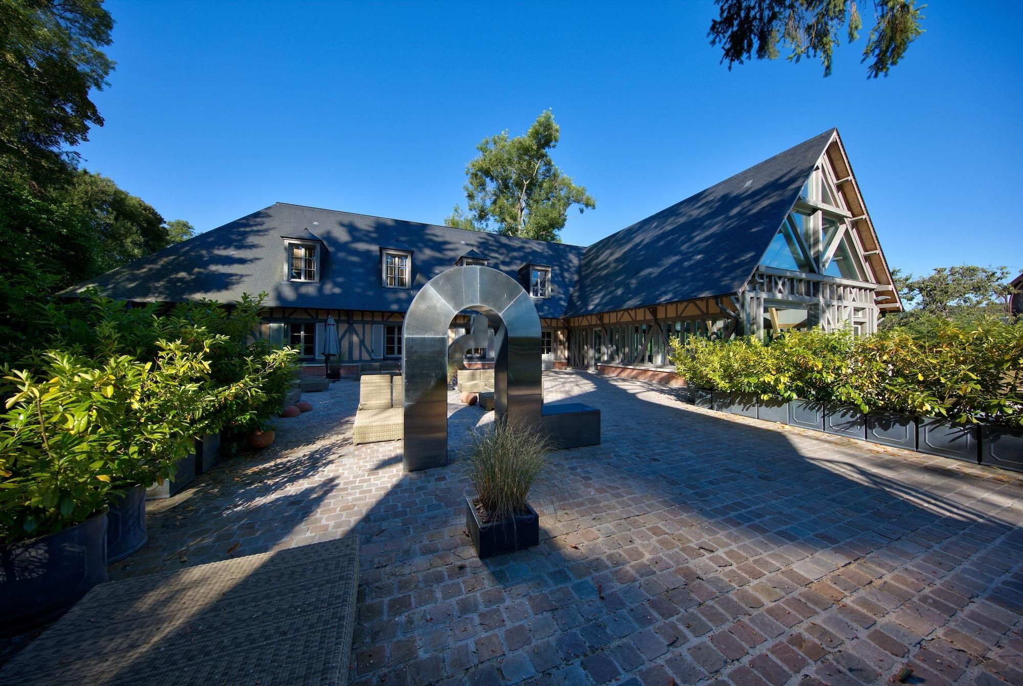 A courtyard with a stone archway, a building with a steep roof, and a paved walkway.