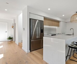 Eine moderne Küche mit einem Edelstahl-Kühlschrank, weißen Schränken und einer großen Kücheninsel mit Spüle.
